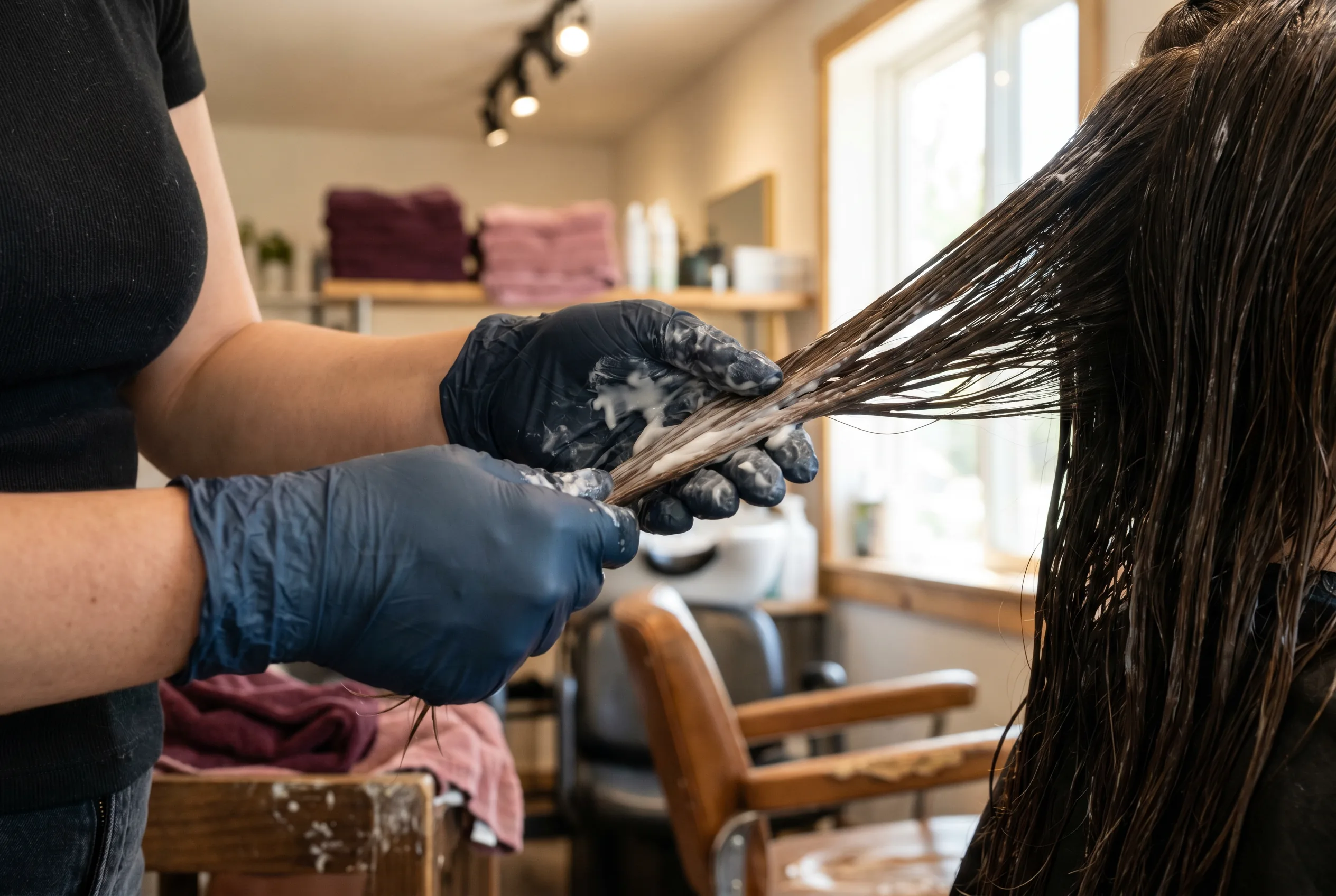 Manos aplicando tratamiento capilar en cabello mojado, Peluquería Dubón Lucena